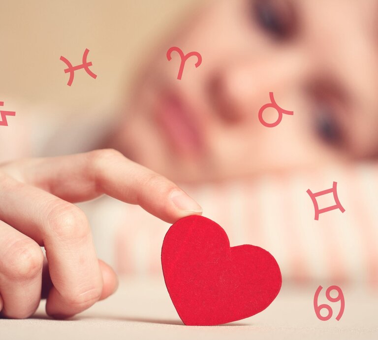 Die Hand einer Frau wiegt ein rotes Herz, umgeben von den Symbolen der Tierkreiszeichen. | © Adobe Stock/ Andrei Korzhyts und Chikovnaya via Canva.com [M]