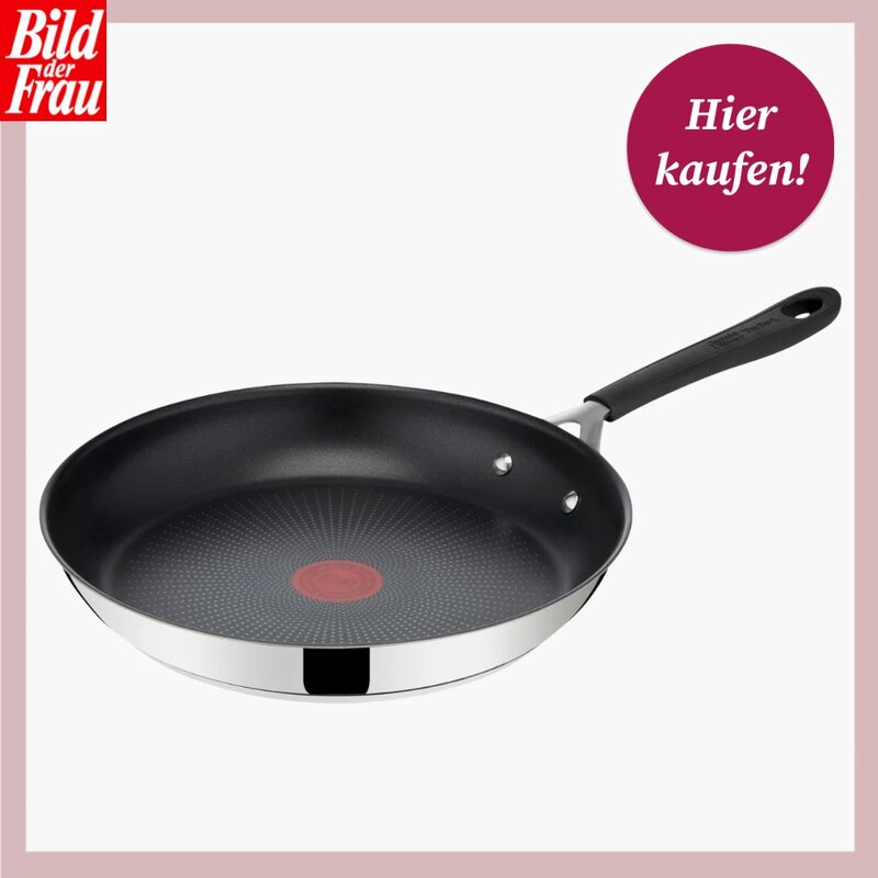Tefal Bratpfanne aus der Jamie-Oliver-Kollektion, freigestellt vor weißem Hintergrund mit roséfarbenem Rand. Die Pfanne hat einen glänzenden Edelstahlkorpus mit schwarzer Antihaft-Beschichtung im Innenbereich. In der Mitte des Pfannenbodens ist der charakteristische rote Tefal-Thermo-Signal-Indikator zu erkennen, der anzeigt, wann die ideale Brattemperatur erreicht ist. Der schwarze Softgrip-Stiel ist ergonomisch geformt und verfügt am Ende über eine Aufhängeöse. Links oben das „Bild der Frau"-Logo, rechts oben ein runder magentafarbener Störer mit der Aufschrift „Hier kaufen!". | © Lidl/ Tefal