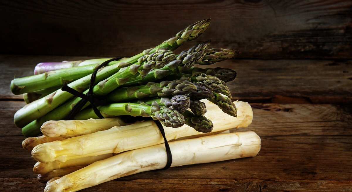 gebundener weißer und grüner Spargel auf Holzuntergrund.