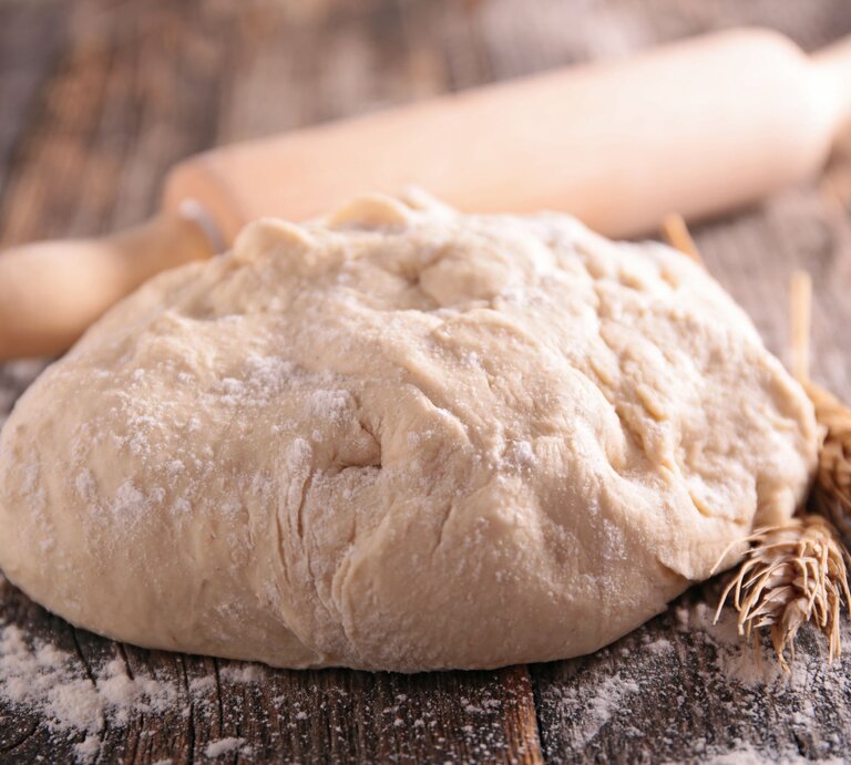 Brotteig mit Nudelholz auf hölzerner Oberfläche.  | © GettyImages/margouillatphotos