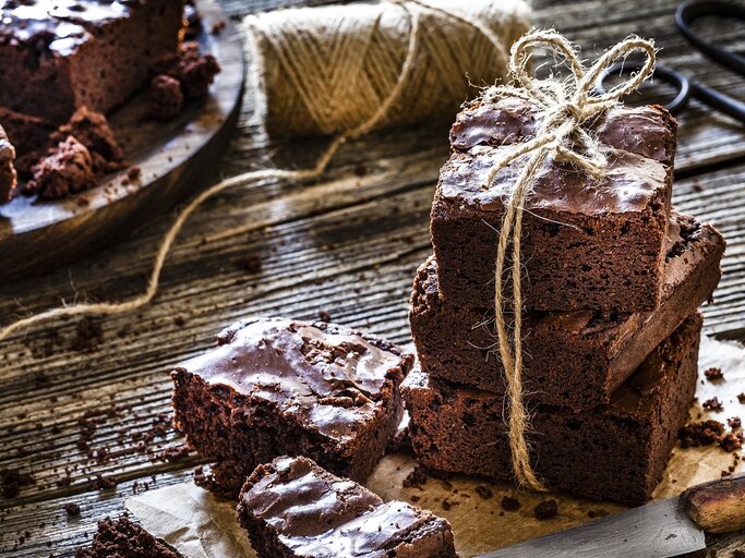 Klassische Brownies, mal einzeln, mal gestapelt / Untergrund grobes Holz /  Messer aus Metall / Kuchengitter /  | © Gettsy Images / fcafotodigital