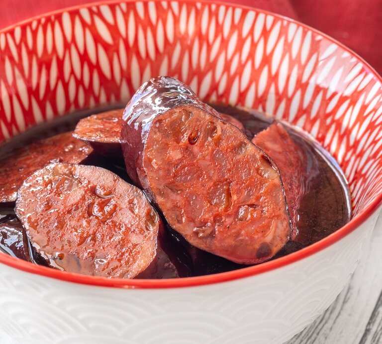 Eine weiß-rote Schale mit dem Tapasgericht auf einem hellen Holztisch. Alles von schräg oben fotografiert. | © Shutterstock/ Alexander Prokopenko