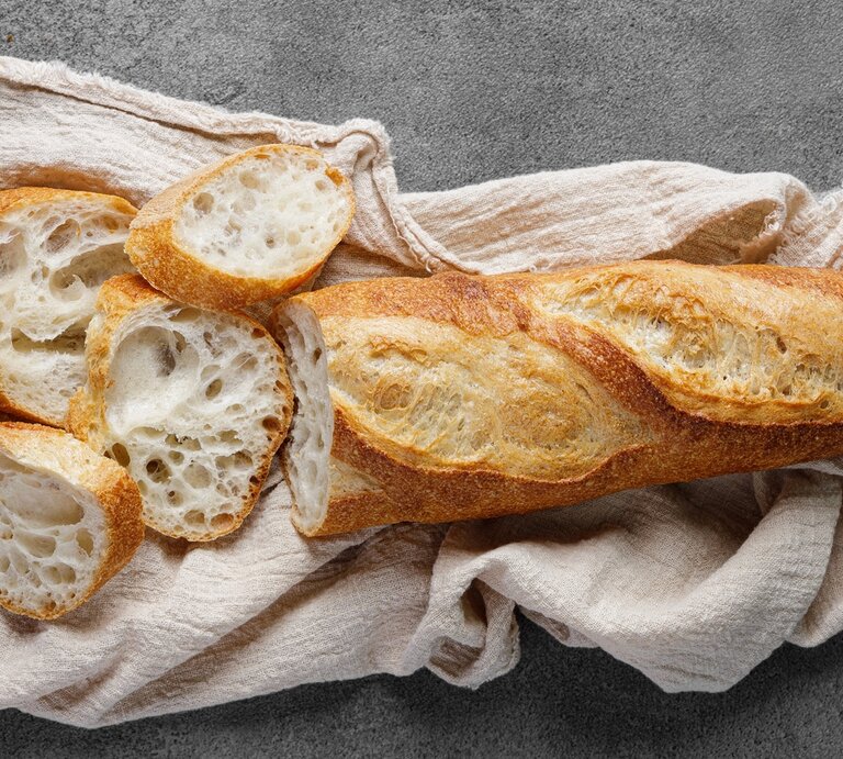 Das Baguette auf einem grauen Tisch mit beiger Tischdecke. Alles von oben fotografiert. | © Shutterstock/ 77 Studio