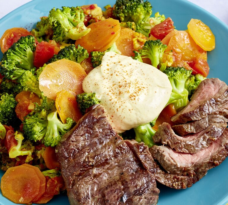 Hüftsteak mit Brokkoli-Möhren-Mix und griechischem Joghurt auf rundem Teller / Draufsicht, schräg | © EAT CLUB / Myriam Banderob