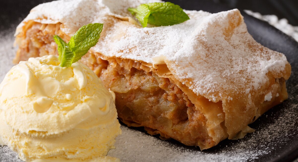 Stück Apfelstrudel auf Teller, daneben Vanilleeis.