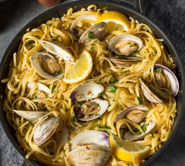 Ein schwarzer Teller mit einer Portion Spaghetti Vongole auf einem grauen Tisch von oben fotografiert | © GettyImages/ bhofack 2