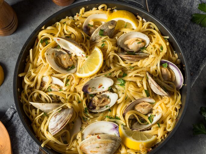 Ein schwarzer Teller mit einer Portion Spaghetti Vongole auf einem grauen Tisch von oben fotografiert | © GettyImages/ bhofack 2
