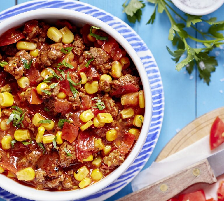 Eine Schale Chili con Carne in einem weiß-blauen Teller auf dem blauen Tisch. Alles direkt von oben fotografiert. | © EAT CLUB/ Isabell Triemer