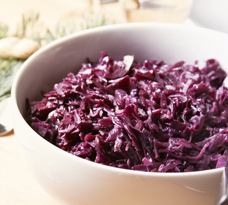 Eine weiße Schale mit dem Rotkohl auf einem hellen Holztisch von schräg oben fotografiert. | © GettyImages/ SilviaJansen