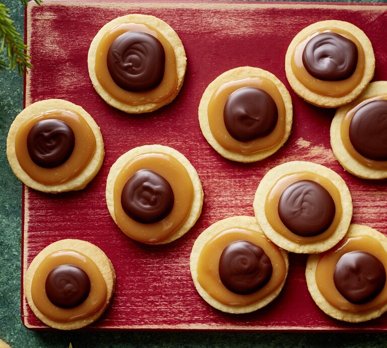 Die Toffifee-Taler auf einem rötlichen Schneidebrett und weihnachtlicher Deko drumherum. Alles direkt von oben fotografiert. | © EAT CLUB/ Isabell Triemer