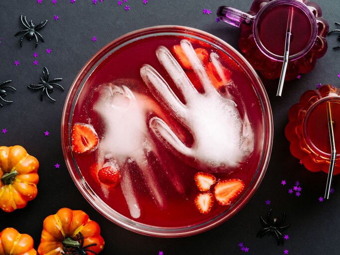 Draufsicht auf eine blutrote Fruchtbowle, in der eine gefrorene Hand aus Wasser liegt.  | © AdobeStock/photoguns