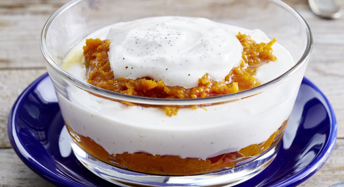 Nahaufnahme einer einer kleinen Glasschüssel mit dem Kürbis-Quark-Schichtdessert. 