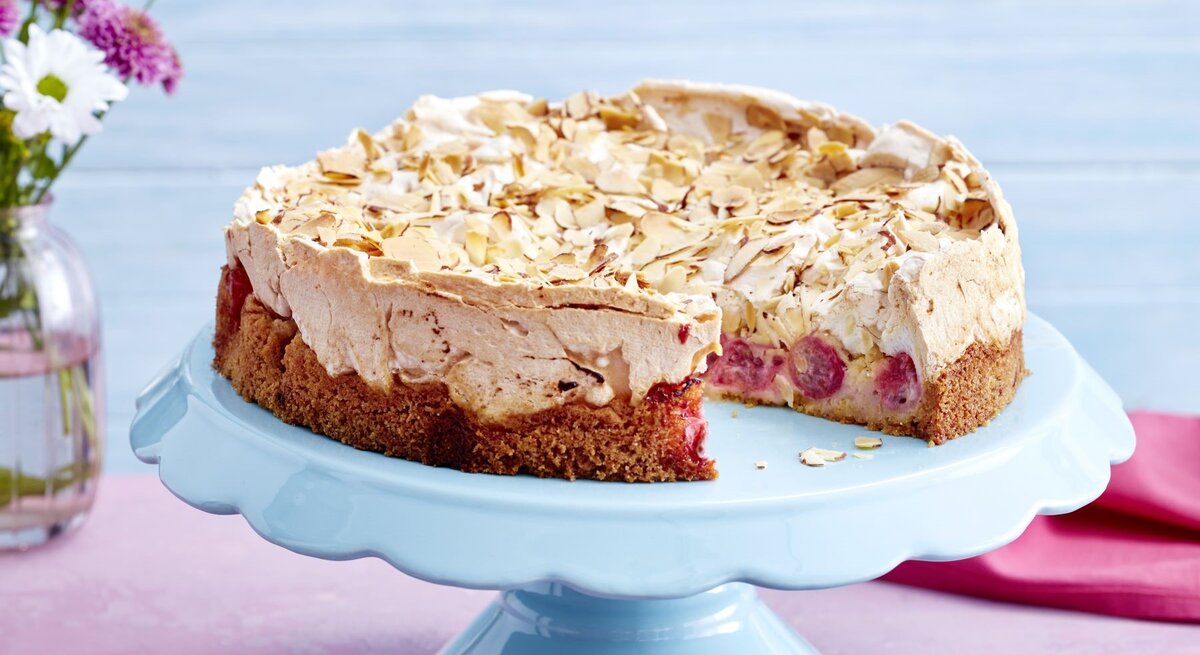 Der Kuchen angeschnitten auf einer Torten-Etagere mit pastelblauem Hintergrund.