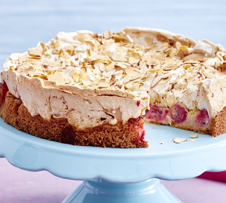 Der Kuchen angeschnitten auf einer Torten-Etagere mit pastelblauem Hintergrund. | © EAT CLUB/ Isabell Triemer