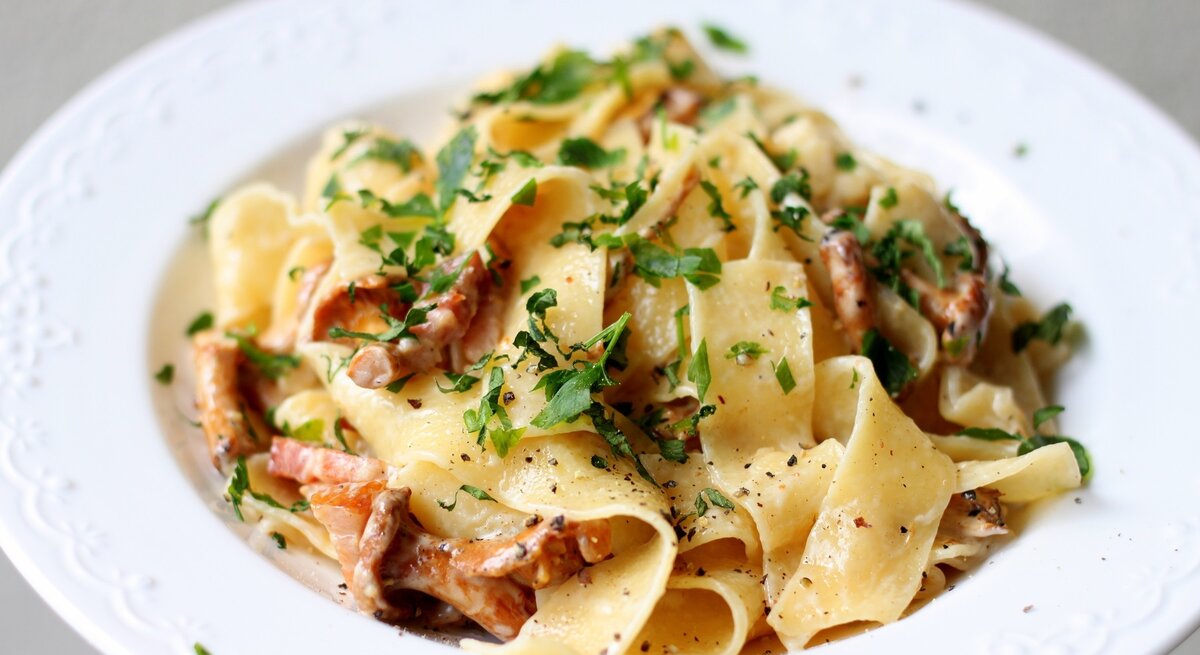 Ein weißer Teller auf weißem Untergrund mit der Pasta. Alles sehr nah und detailliert fotografiert.