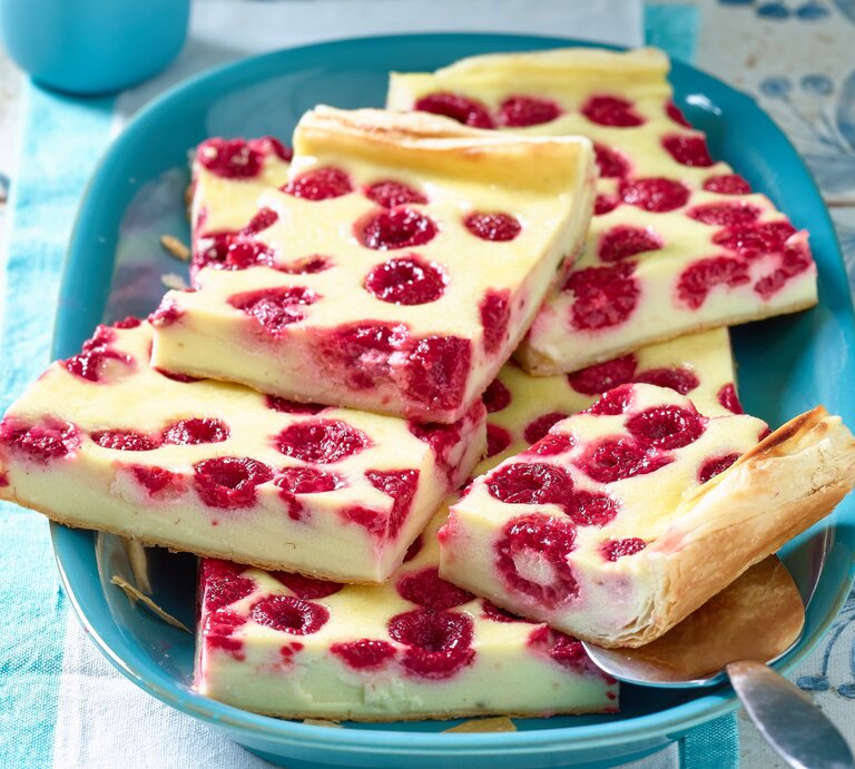 Türkisfarbener Teller mit Stücken von Himbeer-Käsekuchen, appetitlich angerichtet auf rustikalem Untergrund. | © Matthias Liebich