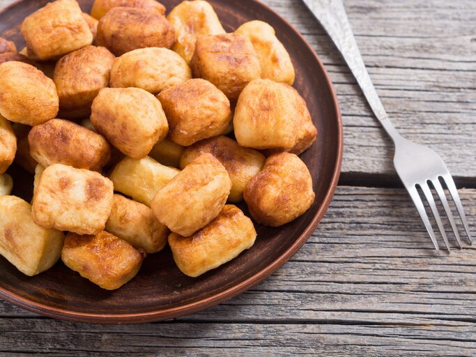 Kross frittierte Gnocchi auf braunem Teller auf einem Holztisch.  | © AdobeStock/whitestorm