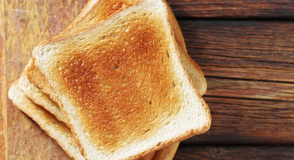 Mehrere getoastete Scheiben Toastbrot auf einem Holzbrett. 
