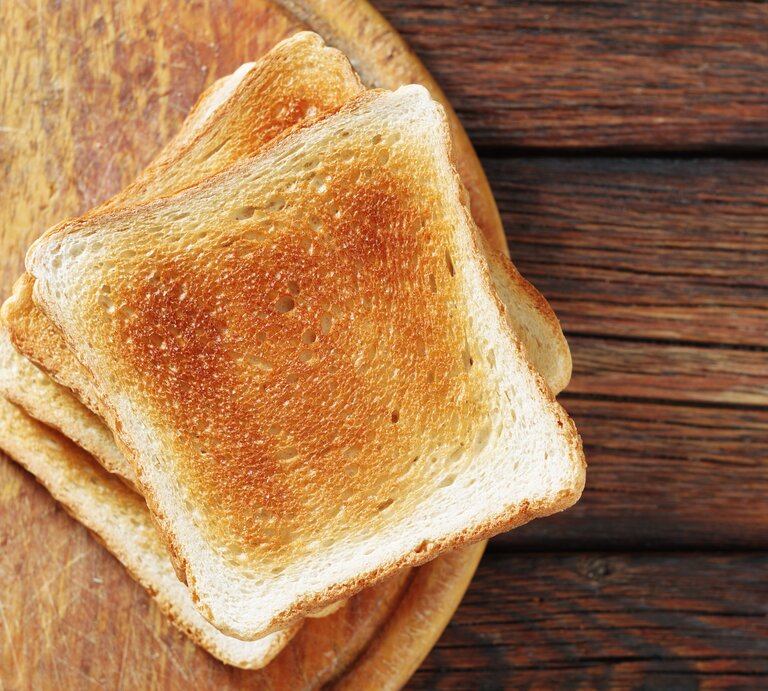 Mehrere getoastete Scheiben Toastbrot auf einem Holzbrett.  | © Shutterstock/Aleksandrs Samuilovs