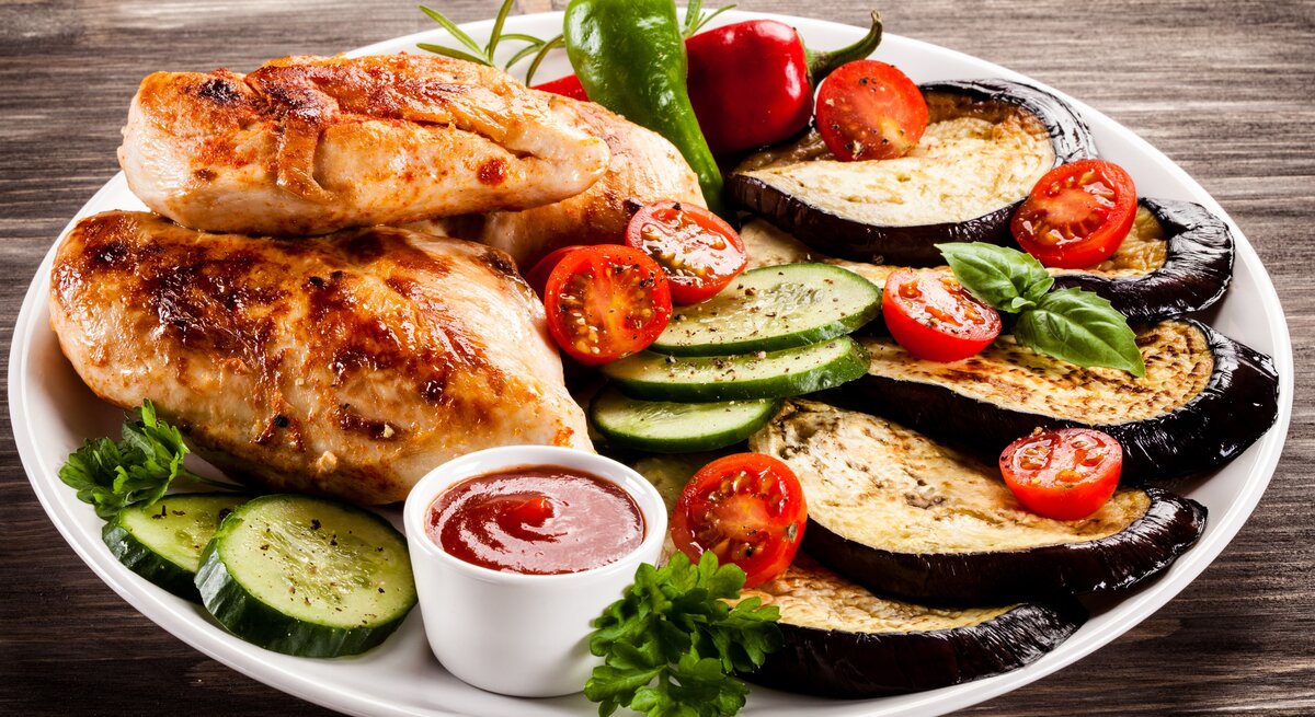 Ein Teller mit Hähnchen und gegrilltem Gemüse. 