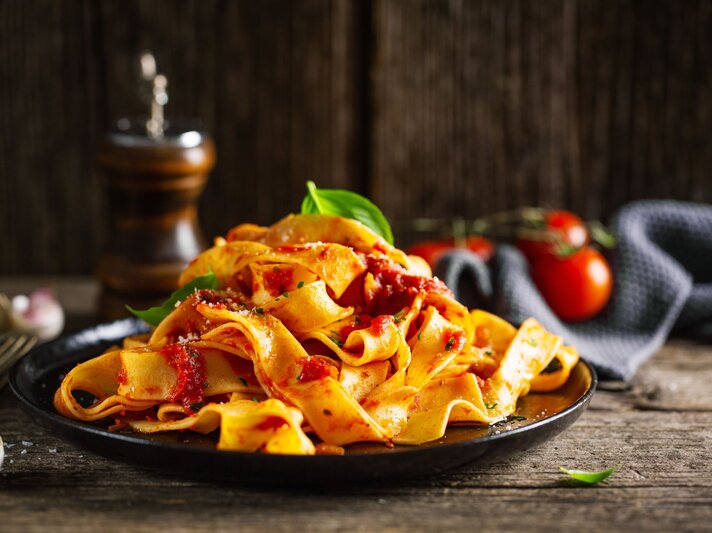 Low-Carb-Nudeln aus Mozzarella und Ei an Tomatensoße auf einem schwarzen Teller.  | © AdobeStock/nerudol 