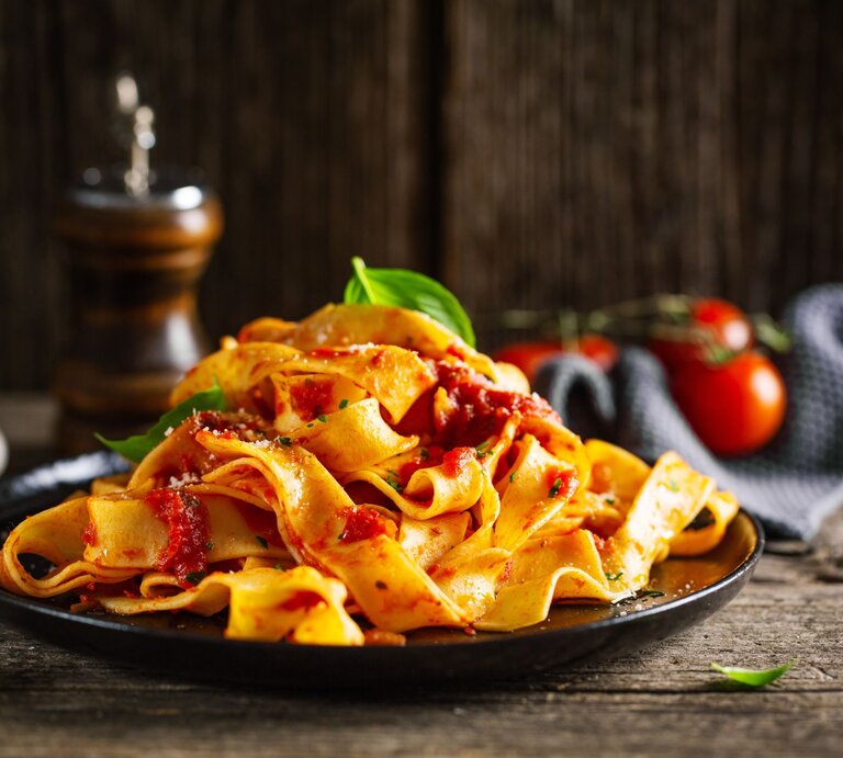 Low-Carb-Nudeln aus Mozzarella und Ei an Tomatensoße auf einem schwarzen Teller.  | © AdobeStock/nerudol 