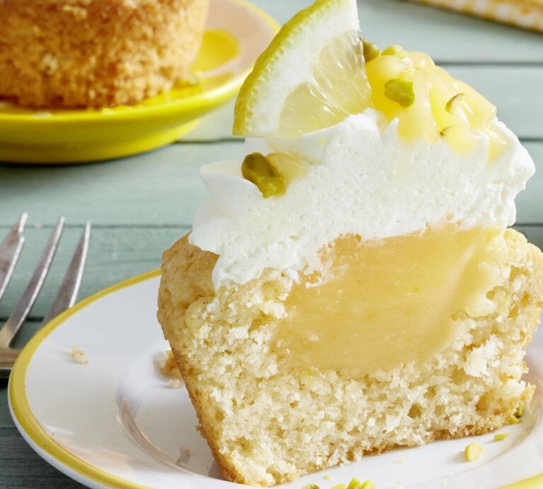 Ein Cupcake auf einem hellen Teller und hellgrünem Holztisch fotografiert | © EAT CLUB/ Isabell Triemer