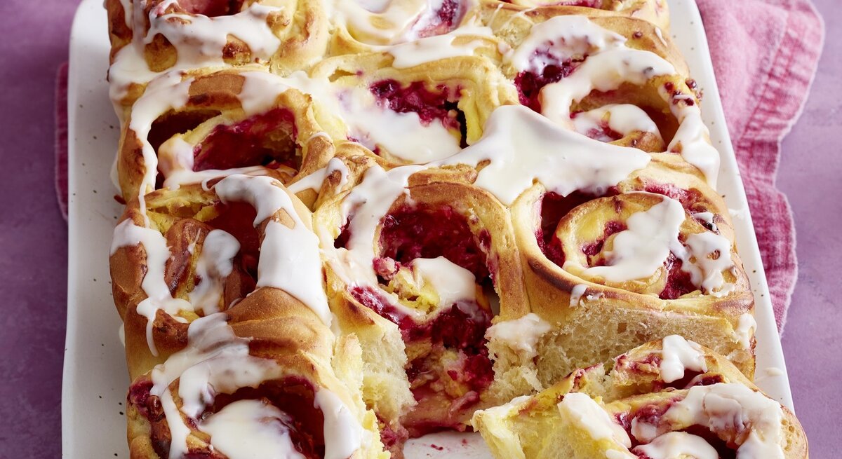 Die Himbeer-Schnecken auf einer weißen Platte und violettem Untergrund. Alles von schräg oben und recht nah fotografiert.