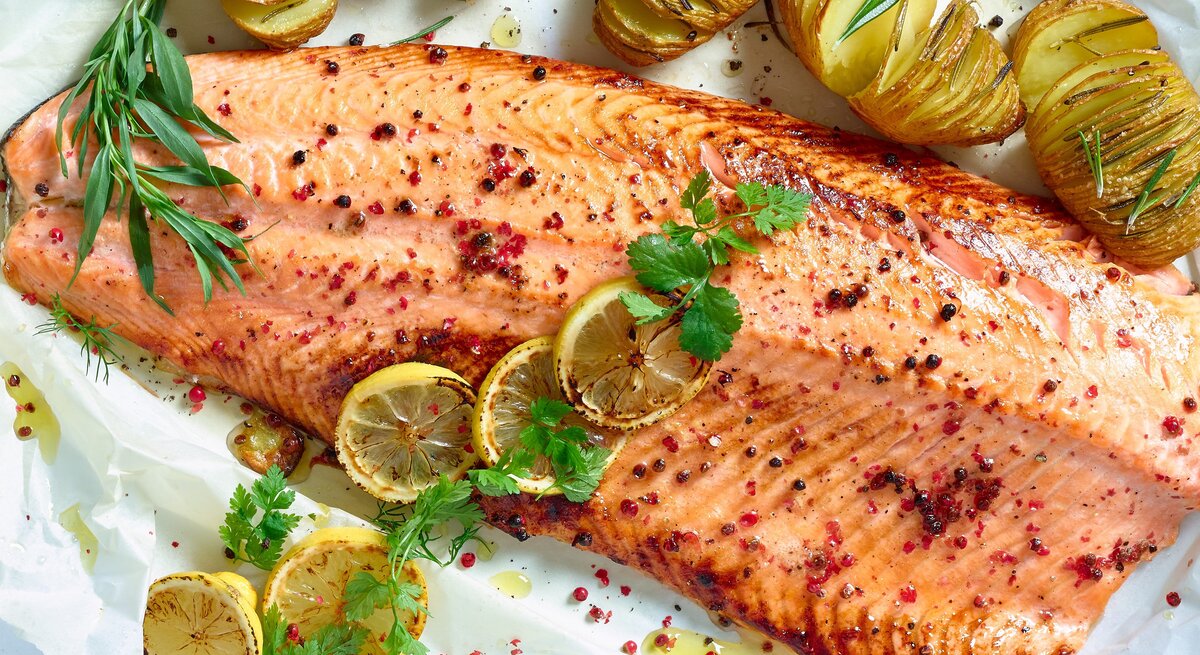 Pulled Lachs gewürzt und mit frischen Kräutern garniert, wird von goldbraun gerösteten Hasselback-Kartoffeln und gegrillten Zitronenscheiben flankiert. 