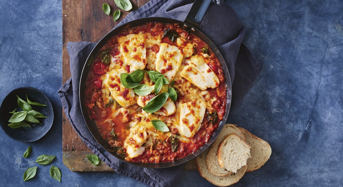 Eintopf mit Hackfleisch und Halloumi / runde Schüssel / drei Scheiben Weißbrot / frische Kräuter / Untergrund Holzbrett 