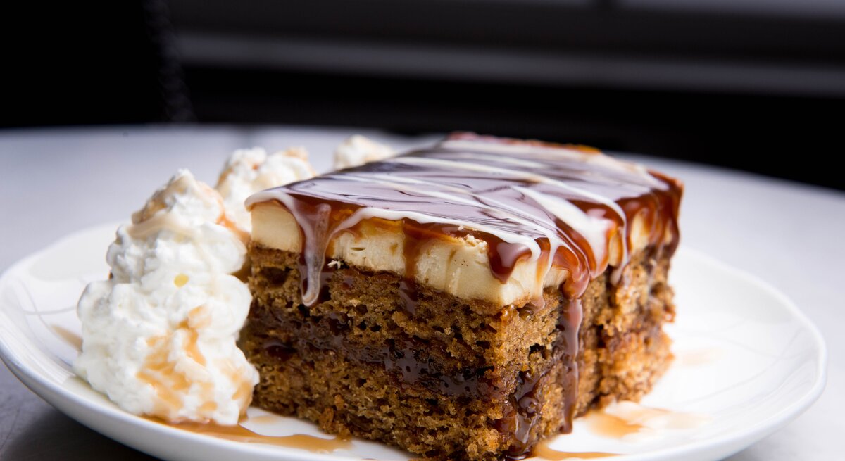 Ein Stück Schmandkuchen mit Karamellsoße und Sahne Teller / / Frontalsicht