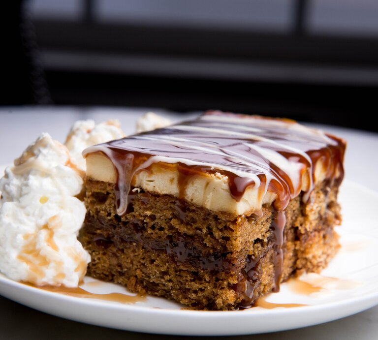 Ein Stück Schmandkuchen mit Karamellsoße und Sahne Teller / / Frontalsicht | © Getty Images / 	Kimberlee Reimer