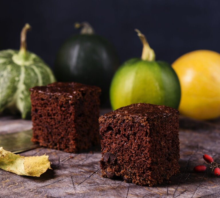 Im Hintergrund sind Zucchinis aus dem Garten zu sehen, vorne zwei schmackhafte Browsnies aus Schokolade und Zucchini. | © gettyimages/ Trendy_Rowdy