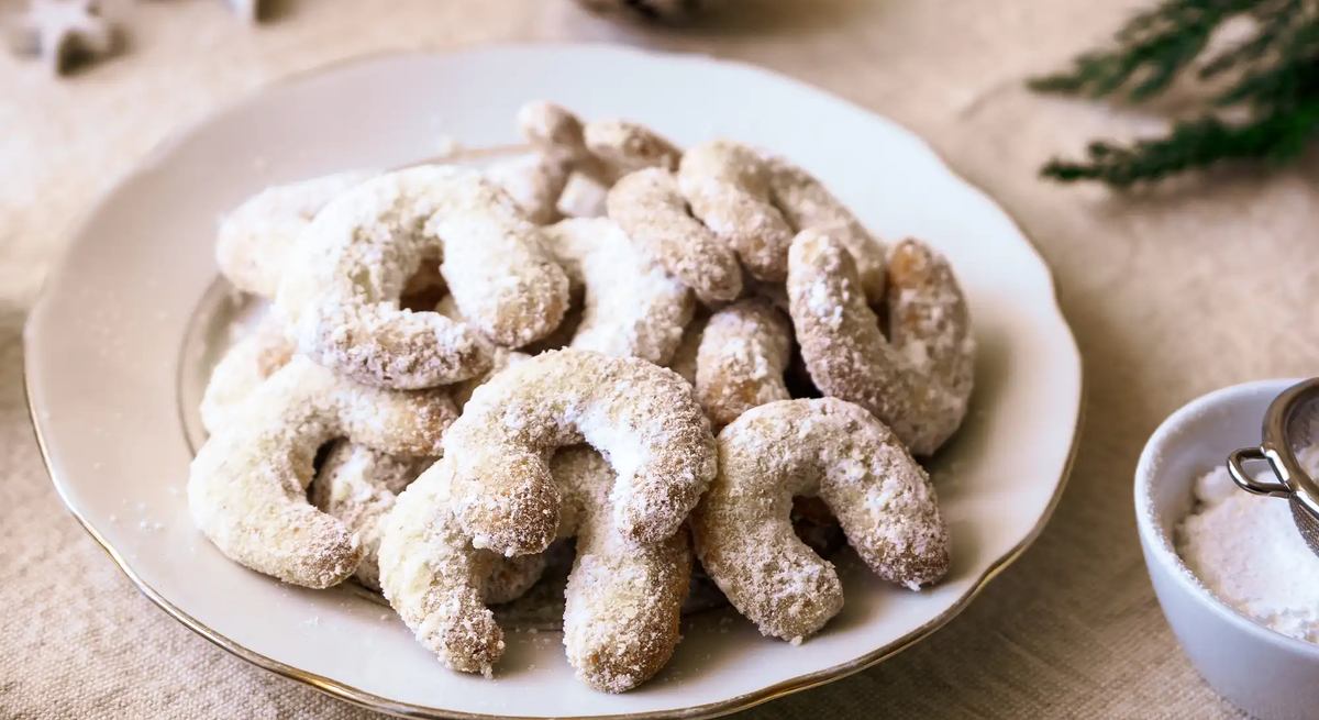 Vanillekipferl auf Teller mit weihnachtlicher Deko auf dem Tisch