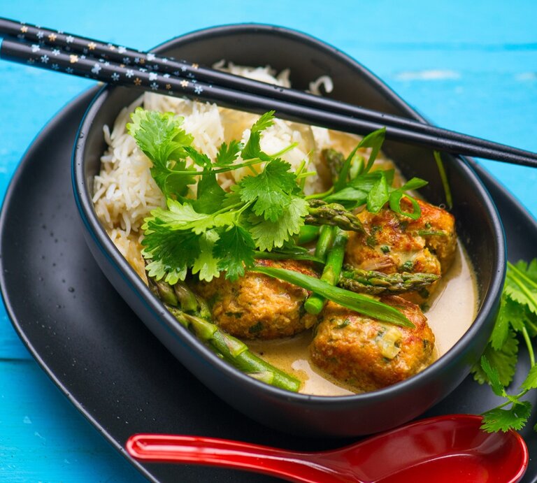 Eine dunkle schale mit der Suppe und Reis auf blauem Untergrund. | © Shutterstock/ Nida Degutiene