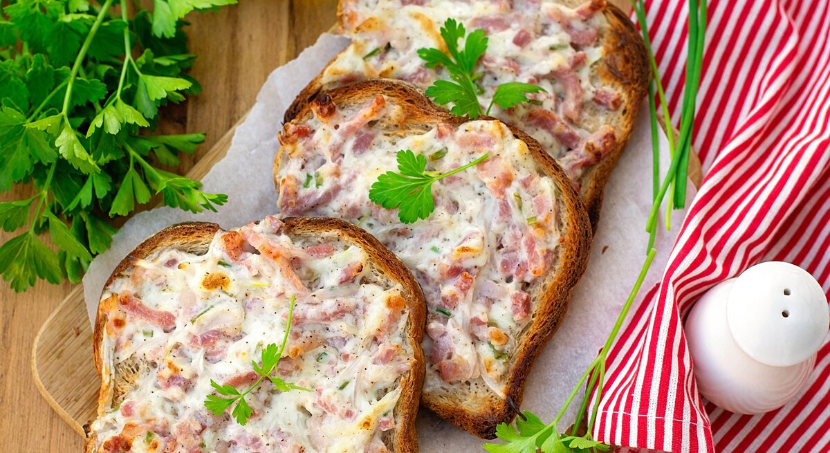 Mehrere Flammkuchen-Toasts auf einem Tisch mit rot-weiß-karierter Tischdecke