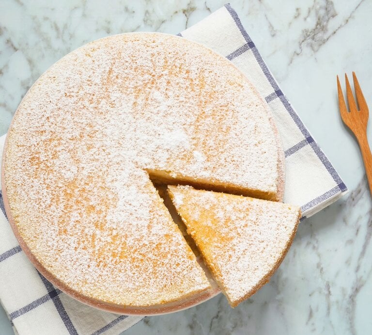 Ein Low Carb Joghurtkuchen von oben fotografiert, ein Stück ist angeschnitten und eine Gabel liegt recht davon auf dem Tisch. | © gettyimages/ p_saranya