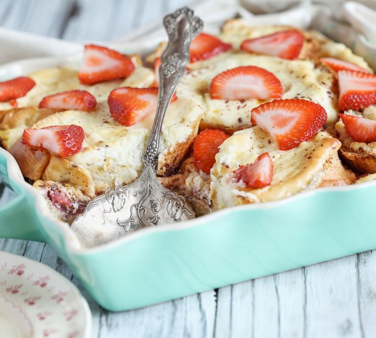 Käsekuchen-Brotauflauf mit Erdbeeren in blauer Auflaufform.  | © Getty Images/StephanieFrey