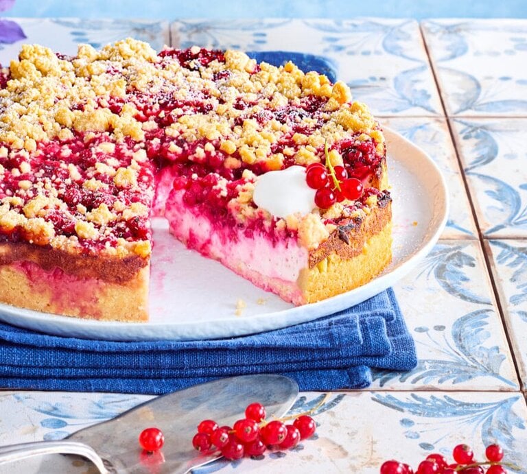 Zu sehen ist ein leckerer Streuselkuchen mit einer Johannesbeercreme, präsentiert vor einem blauen Hintergrund. | © Eat Club