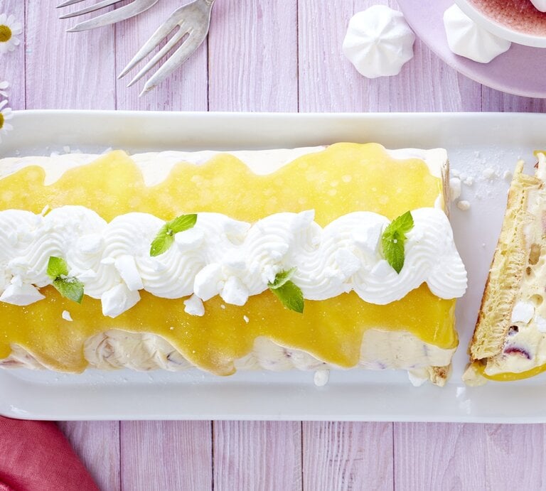 Der Eiskuchen auf einem violetten Tisch mit Blumendeko und auf länglichem weißen Teller angerichtet. Alles direkt von oben fotografiert. | © Isabell Triemer