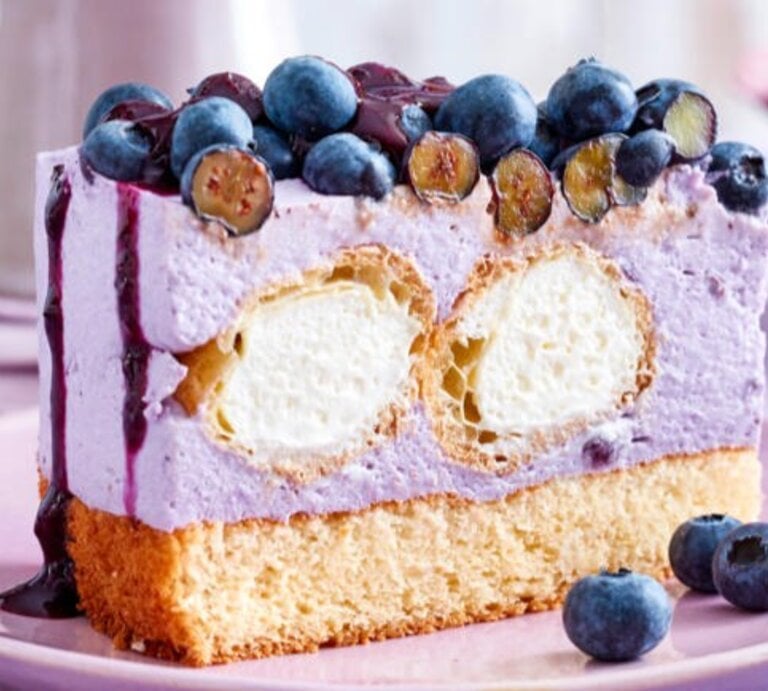Zu sehen ist eine leckere Windbeuteltorte mit Heidelbeeren vor einem lila Hintergrund | © Eat Club