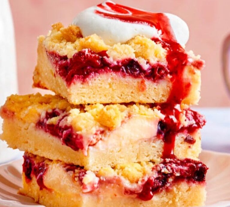 Zu sehen sind Streuselkuchenstücken mit Kirschen und Vanillepudding Füllung, präsentiert vor einem rosa Hintergrund | © Eat Club