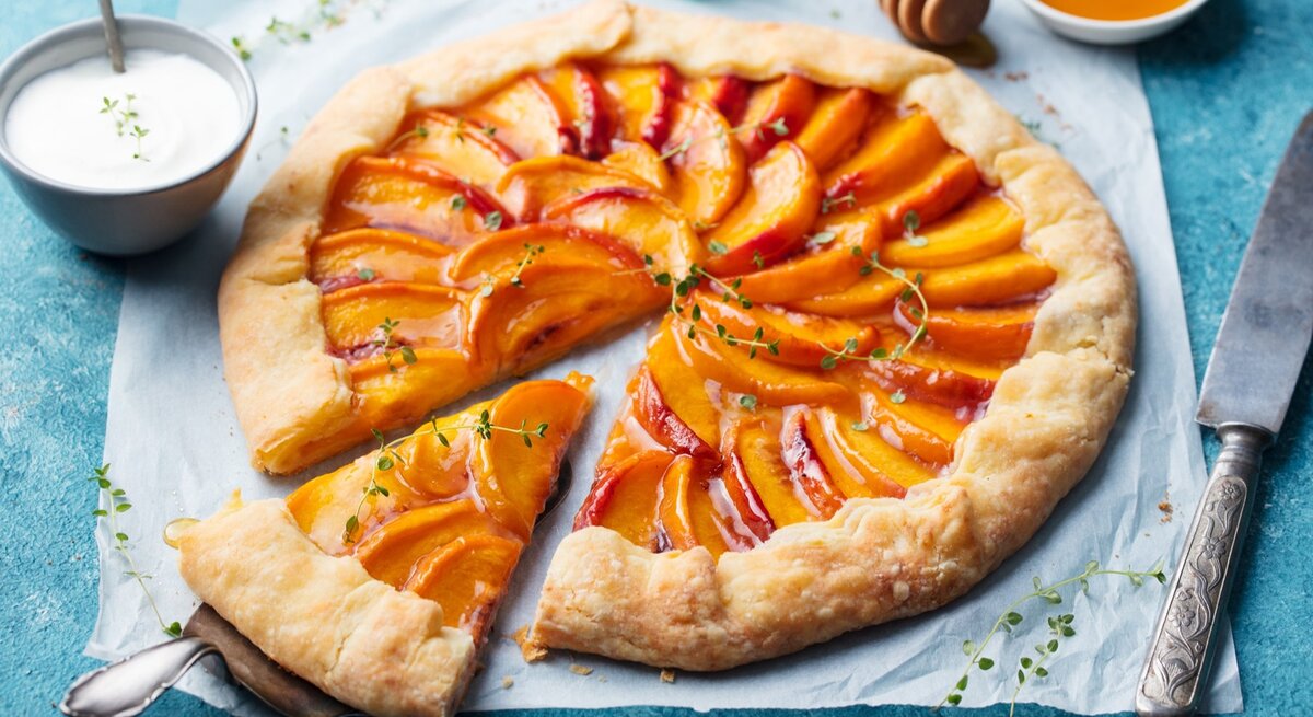 Pfirsich-Galette mit Thymian / Küchenmesser / Schale mit Honig /Nahaufname / Draufsicht