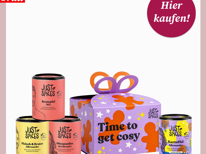 Vier bunte Gewürzdosen von Just Spices stehen neben einer lilafarbenen Geschenkbox mit Schleife und der Aufschrift „Time to get cosy“. | © Just Spices/Canva/Collage:bildderfrau.de
