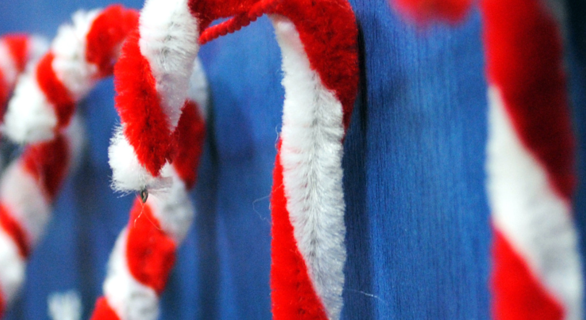 Bunte Weihnachtsdeko aus Pfeifenreinigern: Zuckerstangen, Sterne, Schneemänner, Kränze und Bastelmaterial auf Tischflächen.