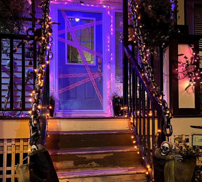 Hauseingang gestalten für Halloween: Mit Lichterketten, Ketten, Skeletten und Spinnennetzen gruselig geschmückter Hauseingang bei Nacht. | © AdobeStock/Oleksandra