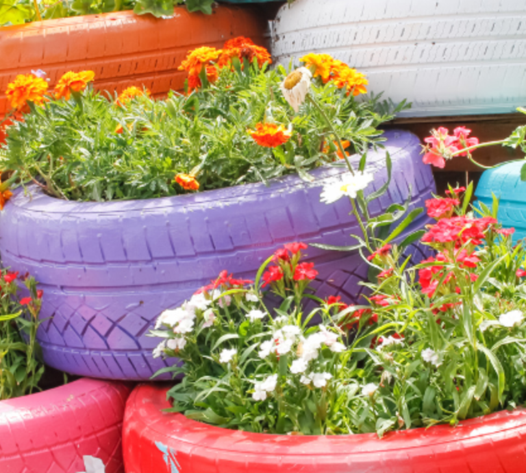 Üppige Blütenpracht in kräftigen Farben zieht sich durch kreative Pflanzgefäße, Blumenrabatten und gepflegte Rasenflächen. Das Ganze umrandet von Beeteinfassungen.  | © Canva/Collage: bildderfrau.de