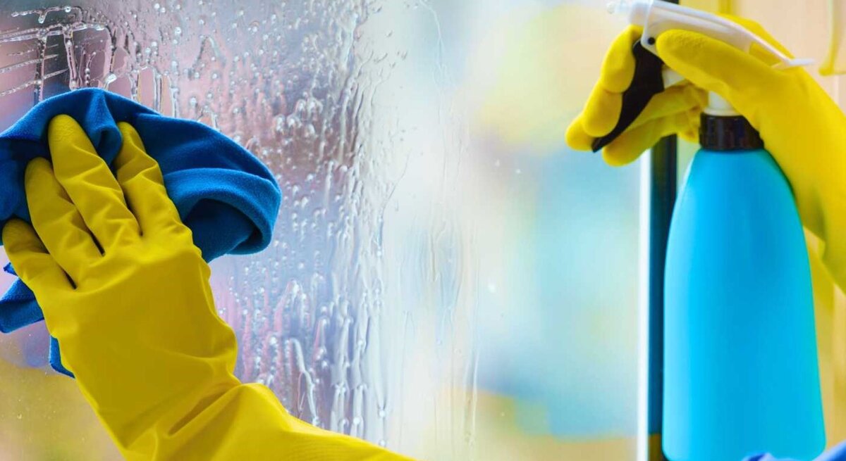 Frau putzt Fenster mit Handschuhen - Nahaufnahme