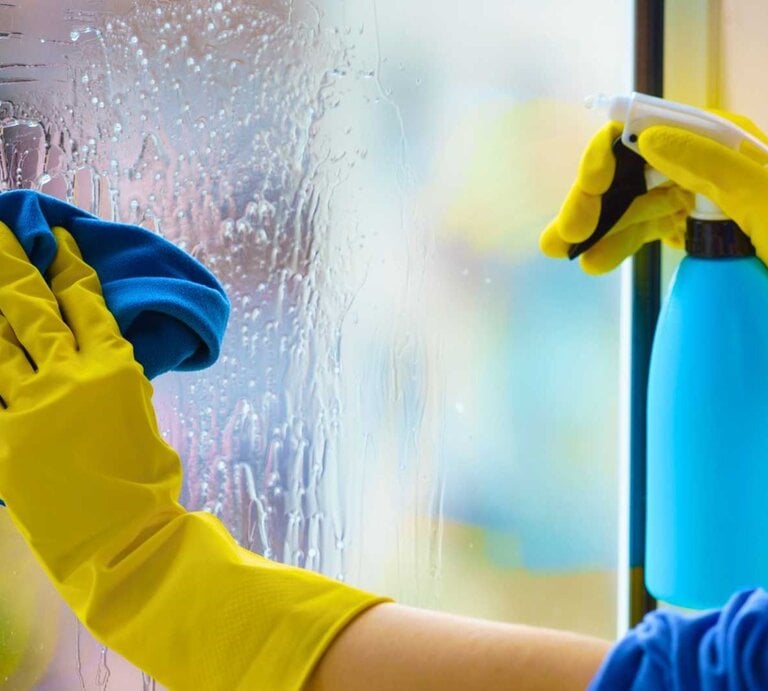 Frau putzt Fenster mit Handschuhen - Nahaufnahme | © Adobe Stock/ Voyagerix