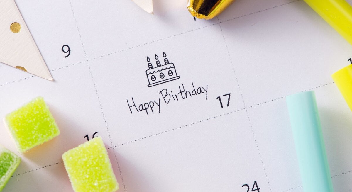 Ein Kalender mit der Markierung "Happy Birthday" am 17., umgeben von bunten Süßigkeiten, Partyhüten und Dekoration.